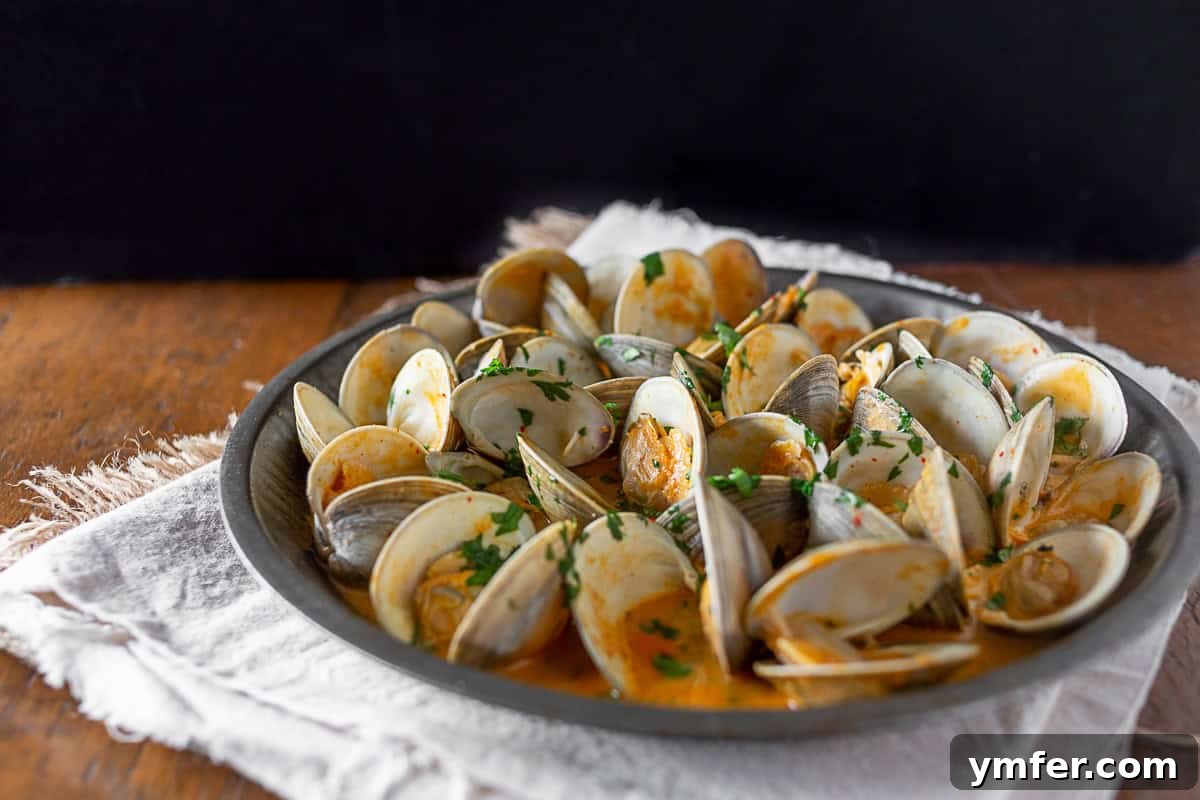 Coco-Chili Clams 5 Spicy Coconut Milk Clams arranged in a serving tray, garnished with cilantro and lime wedges.