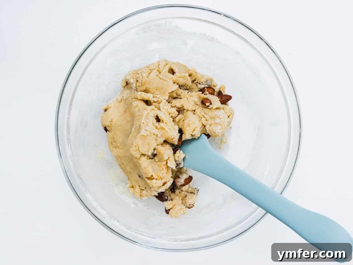 Twice Baked Italian Delights 9 Dry ingredients like flour and baking powder, along with almonds, being mixed into the wet ingredients in a large glass bowl.