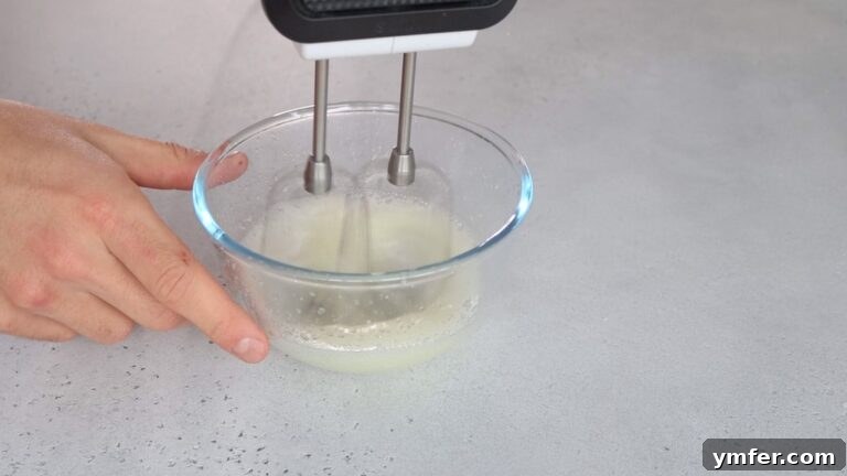 Zesty Orange Almond Delights 8 Whipping aquafaba with an electric whisk until it forms a firm foam.