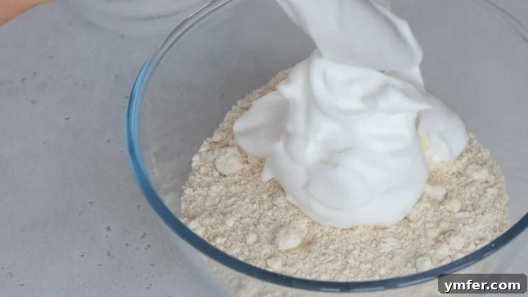Zesty Orange Almond Delights 9 Gently folding whipped aquafaba foam into the dry cookie ingredients with a spatula.
