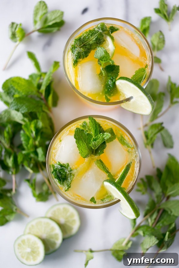 Mango Bliss Mojito 2 A vibrant mango mojito in a stylish glass, garnished with fresh mint and lime slices, set on a elegant marble cutting board.