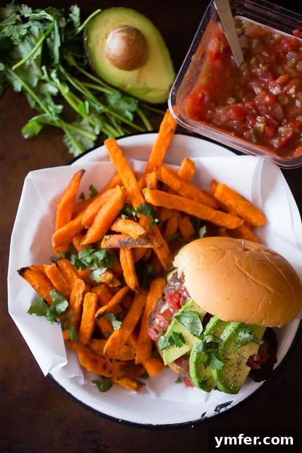 A completed cheesy salsa burger on a bun with avocado, salsa, and cilantro, demonstrating a delicious meal.