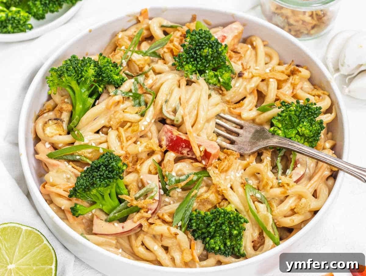 Plant-Powered Mondays 4 Creamy peanut butter noodles topped with fresh broccoli, with a fork ready to serve