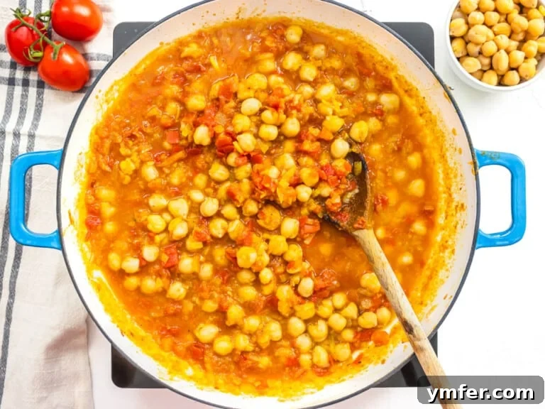 Spiced Chickpea and Spinach Curry 12 Chickpeas and tomatoes simmering in a skillet, forming the curry base.