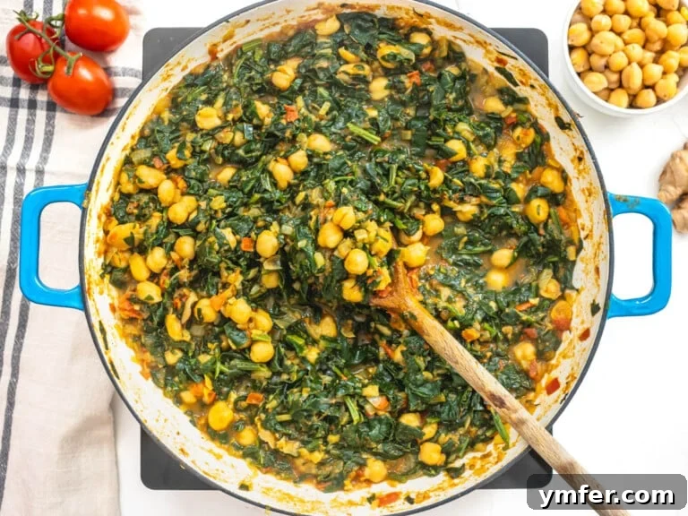Spiced Chickpea and Spinach Curry 13 Cooked chickpeas and spinach in a blue skillet, ready to serve.