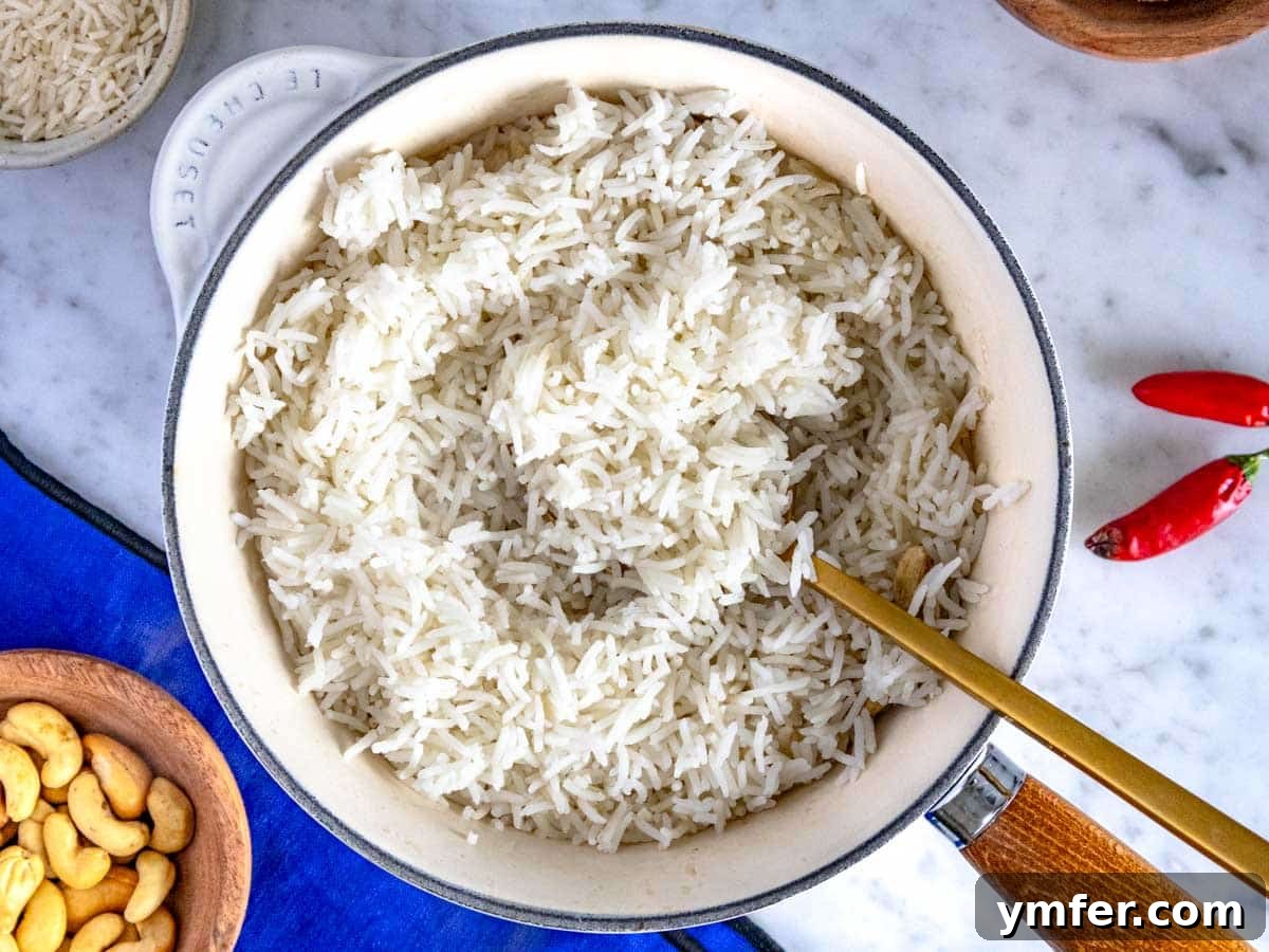Mastering Fluffy Basmati Rice 6 Appetizing fluffy basmati rice served in a rustic white pot, accompanied by scattered cashew nuts and a stylish blue linen cloth, highlighting its inviting texture.