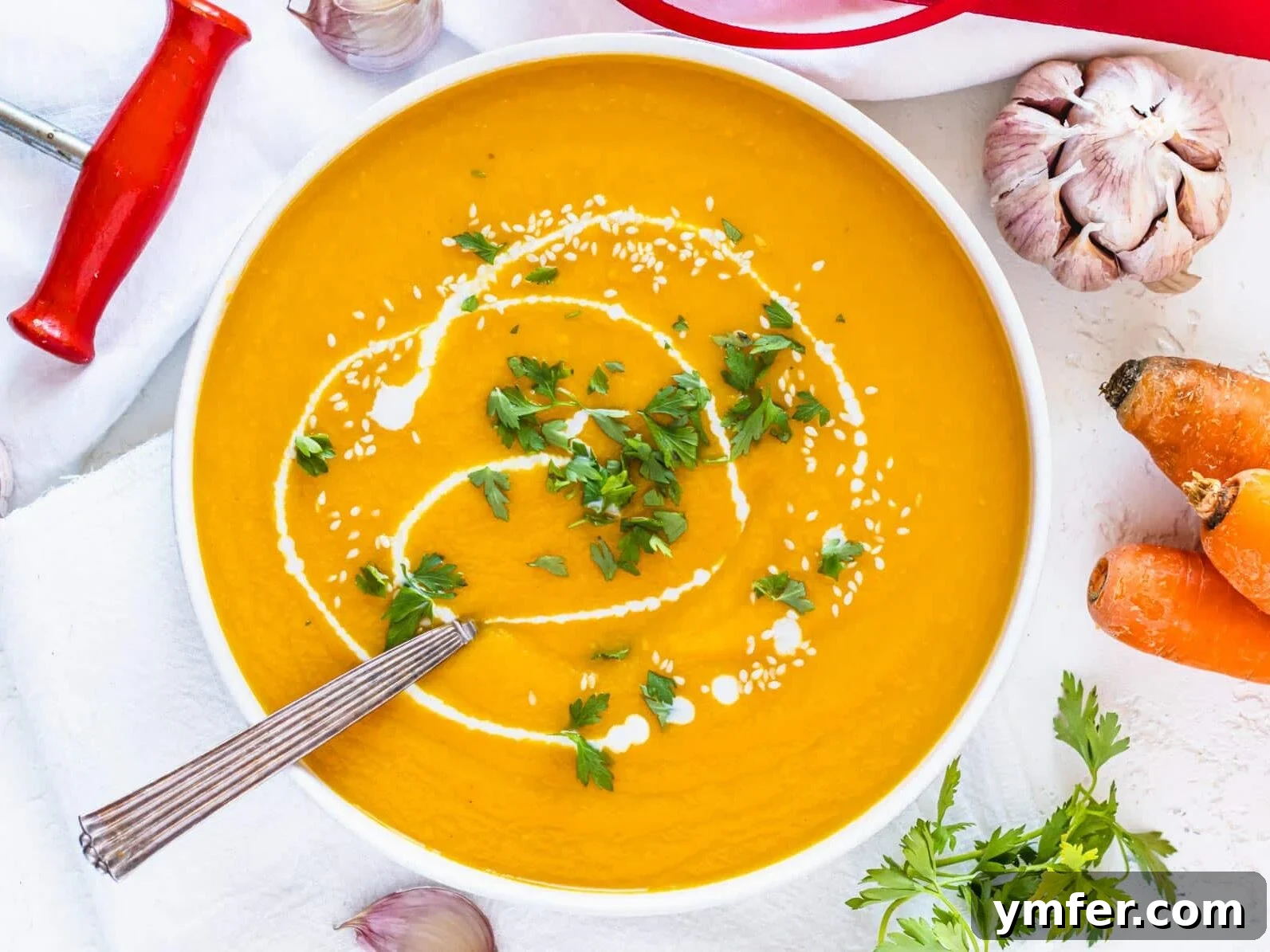 Golden Turmeric Creations 15 carrot soup in a white bowl with silver spoon