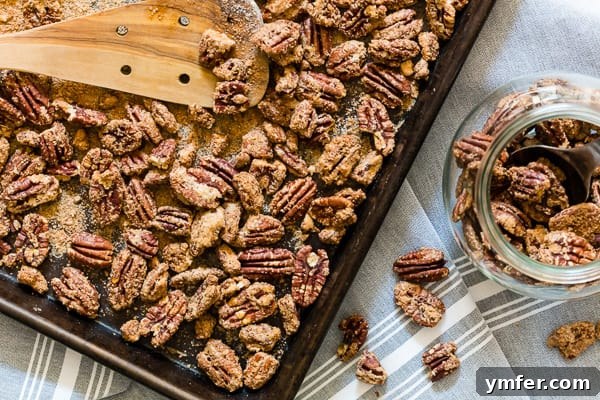 Caramelized Pecan Crunch 6 Praline Pecans being scooped from a sheet pan into a glass gift jar.
