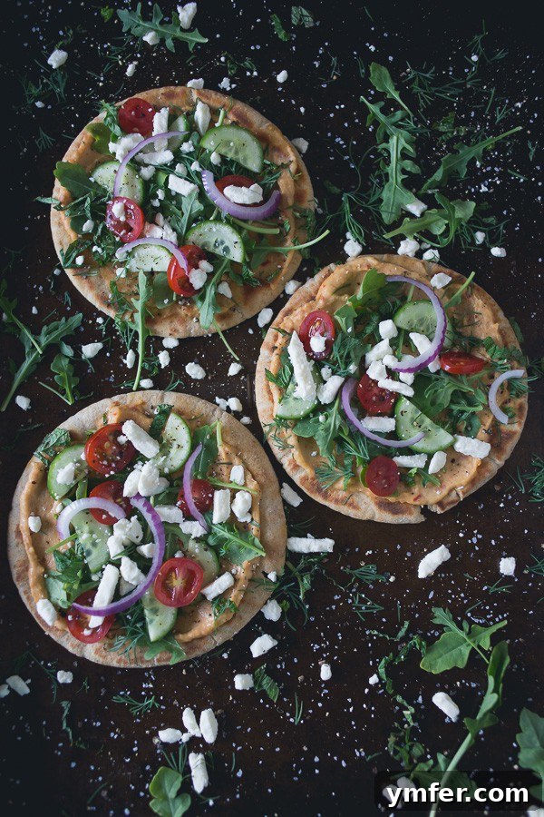 Mediterranean Hummus Pita Pizza 2 Greek Salad Hummus Pita Pizzas: A vibrant and fresh summer appetizer or main course featuring olive oil grilled pita topped with spicy hummus and a crisp Greek salad.