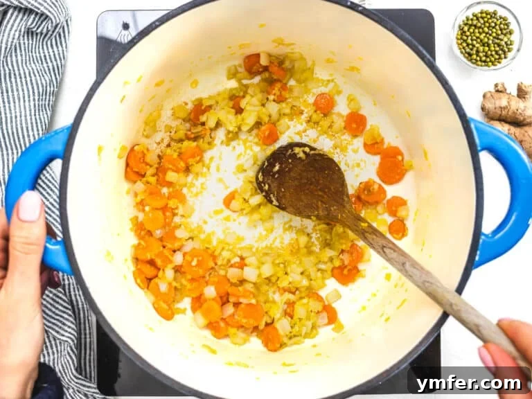 Jade Bean Elixir 14 carrots and onions in a blue casserole and hands holding a wooden spoon