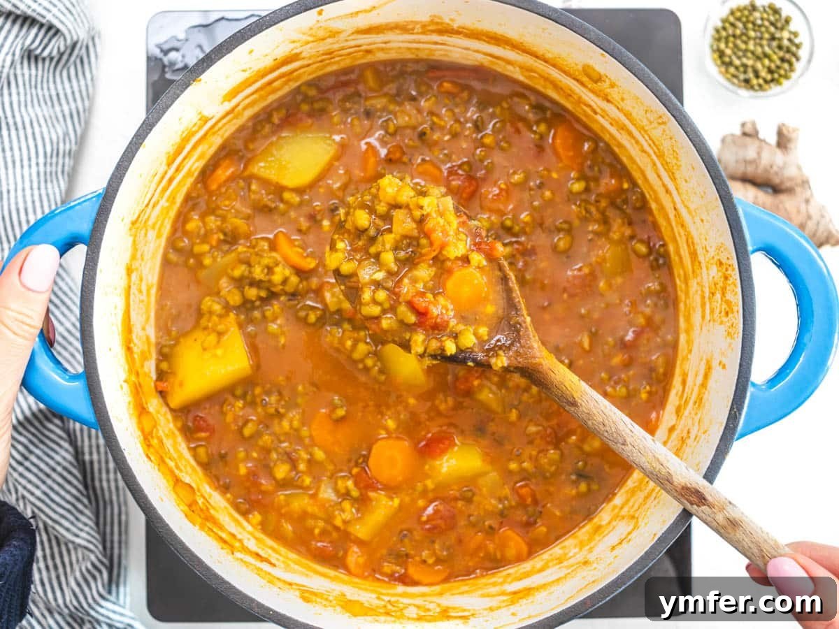 Jade Bean Elixir 10 Mung beans and potatoes cooking in the soup, with a hand holding a wooden spoon