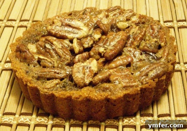 Espresso-Kissed Chocolate Pecan Bites 4 Three Mini Chocolate Espresso Pecan Tarts arranged on a rustic wooden placemat, highlighting their golden crusts and glossy tops.