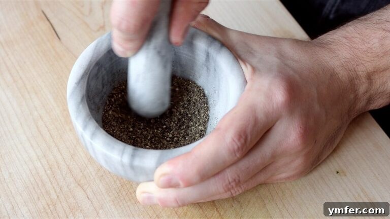 Creamy Vegan Pepper Pasta 18 Crushing toasted peppercorns with a mortar and pestle for a fine pepper dust.