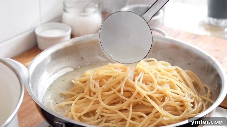 Creamy Vegan Pepper Pasta 22 Adding undercooked spaghetti to the rich vegan cheese sauce in a pan.