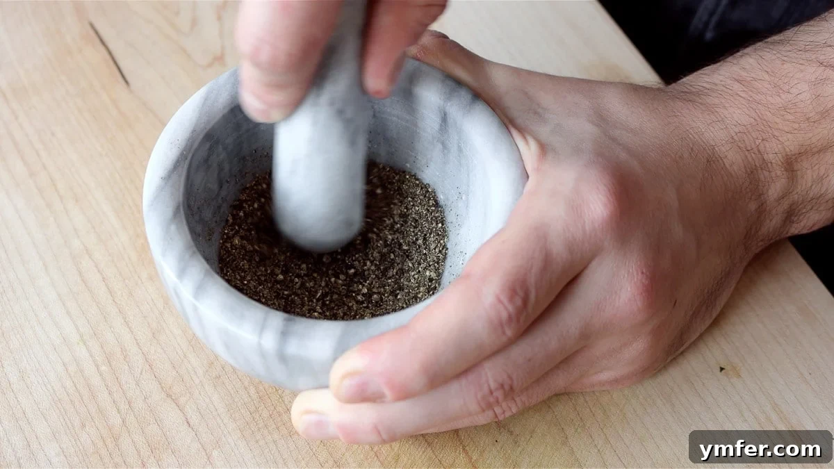 Creamy Vegan Pepper Pasta 7 Freshly toasted black peppercorns being crushed in a mortar and pestle.