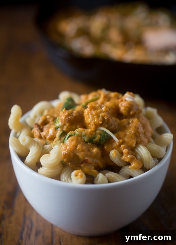 Rustic Spicy Pumpkin Sausage Sauce 3 A close-up shot of the creamy spicy sausage pumpkin pasta sauce, highlighting the rich orange color, bits of sausage, and green spinach flecks, served in a rustic bowl.