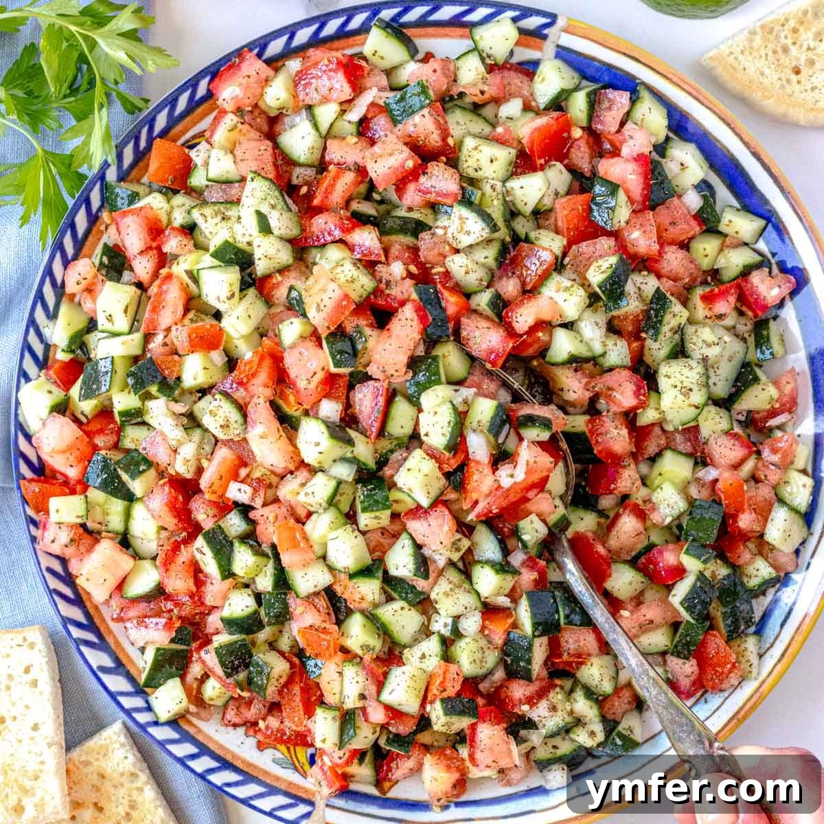 shirazi salad on a blue plate with a silver spoon and pita bread