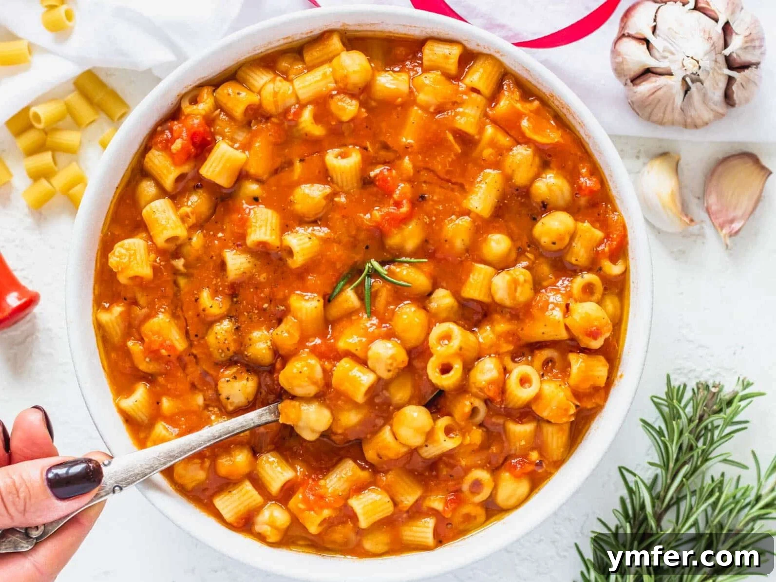 Protein-Packed Pasta Creations 20 Pasta e Ceci in a bowl with a hand holding a spoon, a comforting Italian dish.