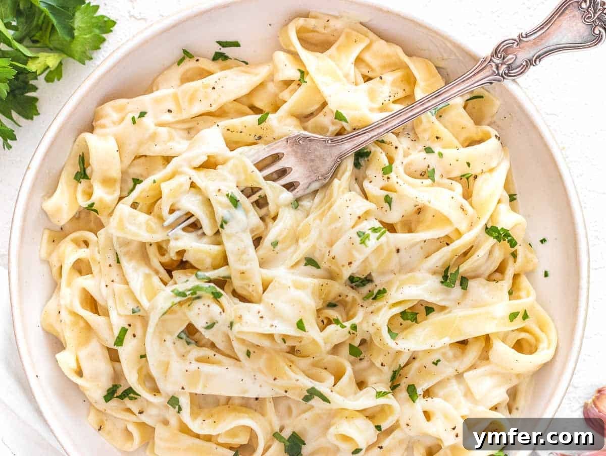 Protein-Packed Pasta Creations 26 Creamy Cauliflower Alfredo pasta with a fork, showcasing its decadent texture.