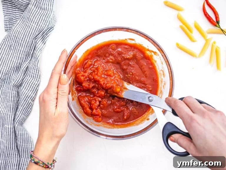 hand and scissors cutting pelati tomatoes into chunks in a bowl