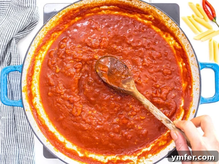 arrabbiata sauce in a blue skillet with a wooden spoon