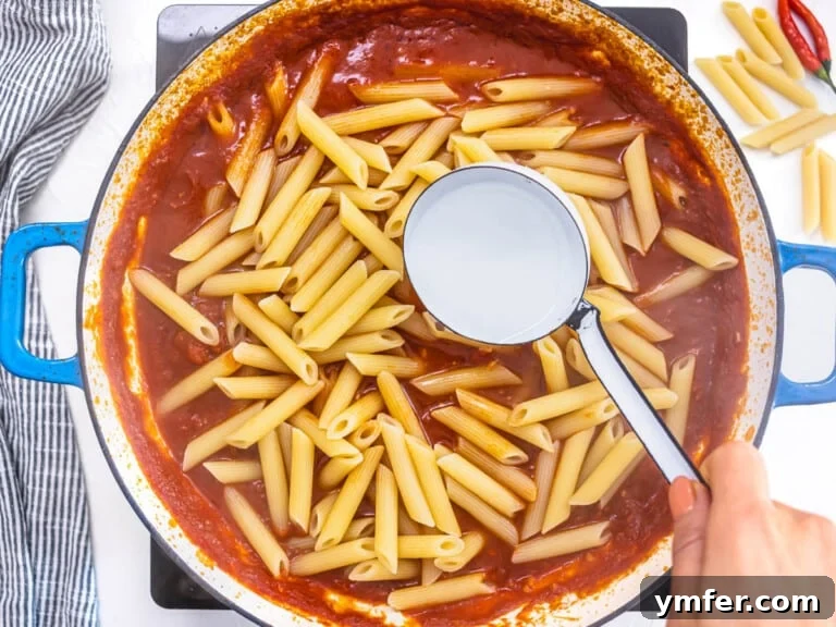 Penne pasta added to a tomato sauce with pasta water