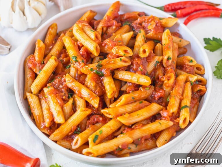 Penne Arrabbiata in a white bowl with fresh parsley