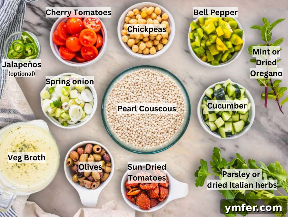 A collection of fresh ingredients for pearl couscous salad laid out on a marble surface.