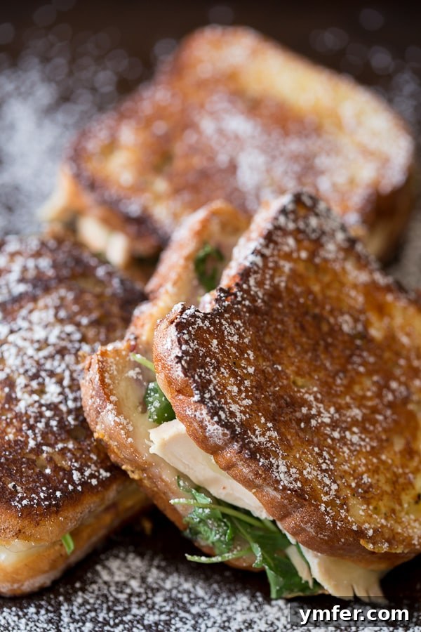 Sultan's Monte Cristo 4 A close-up of a golden-brown Turkey Monte Cristo sandwich dusted with powdered sugar, ready to be served.
