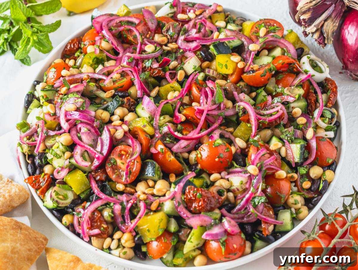 Grecian Summer Salad 5 Prepared Mediterranean salad on a serving platter, garnished with vibrant pickled red onions, ready to be enjoyed.