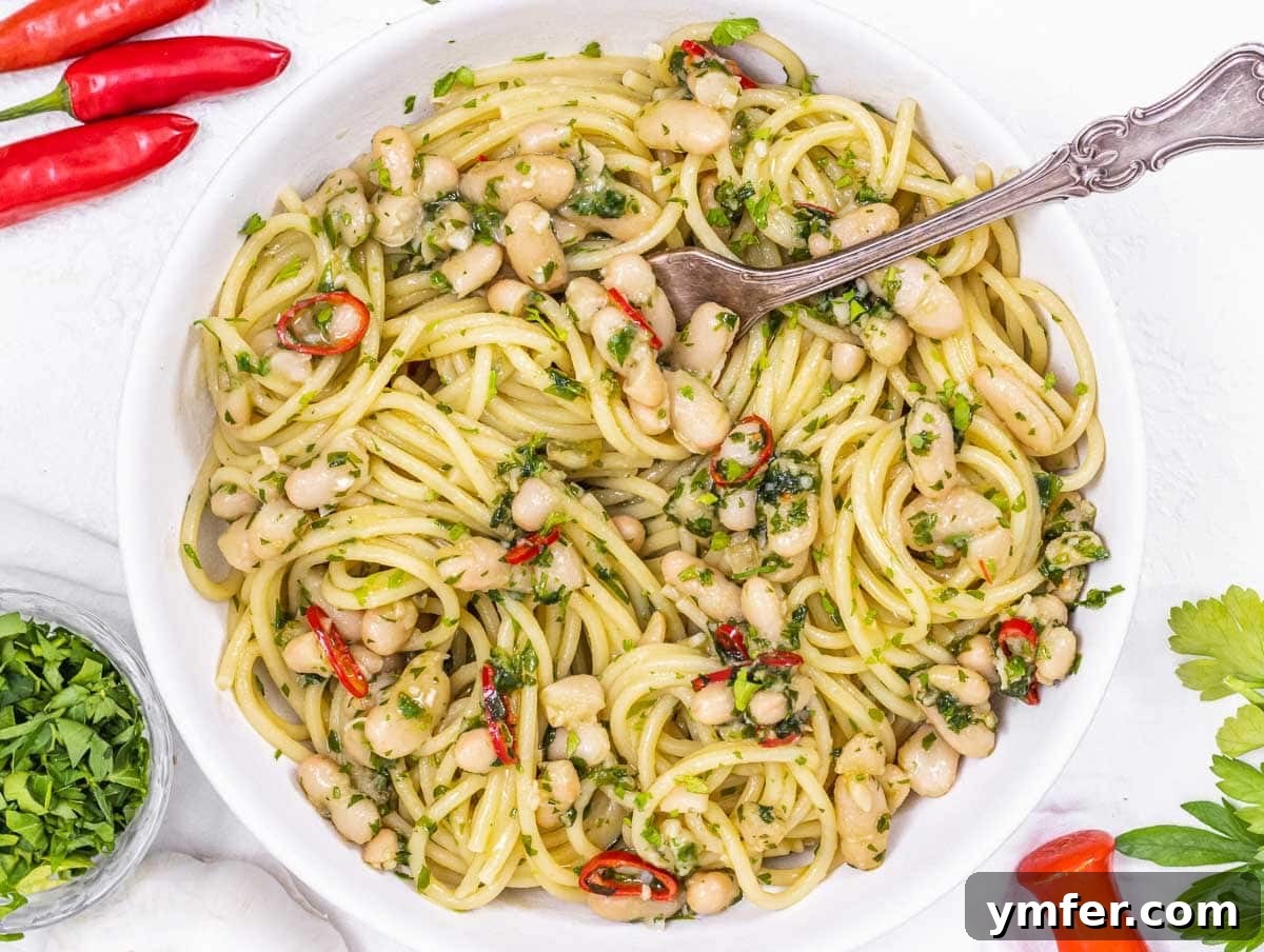 15 Quick and Easy Cannellini Bean Dishes 6 Aglio e olio pasta with white beans and a fork, ready to be enjoyed