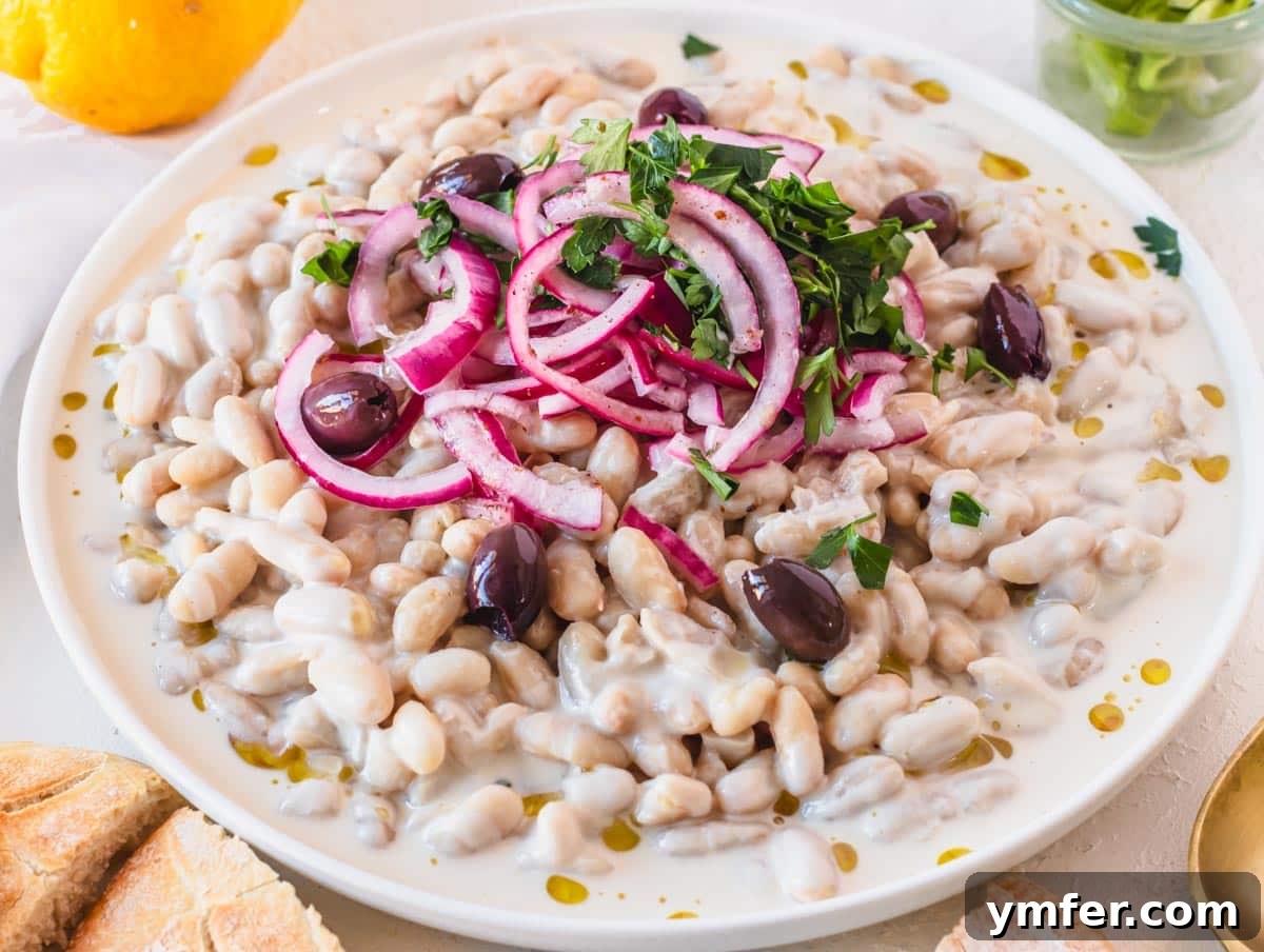 Piyaz Zesty Turkish White Bean Salad 18 A large white plate of Piyaz salad topped with fresh onions and herbs, ready to be served or stored