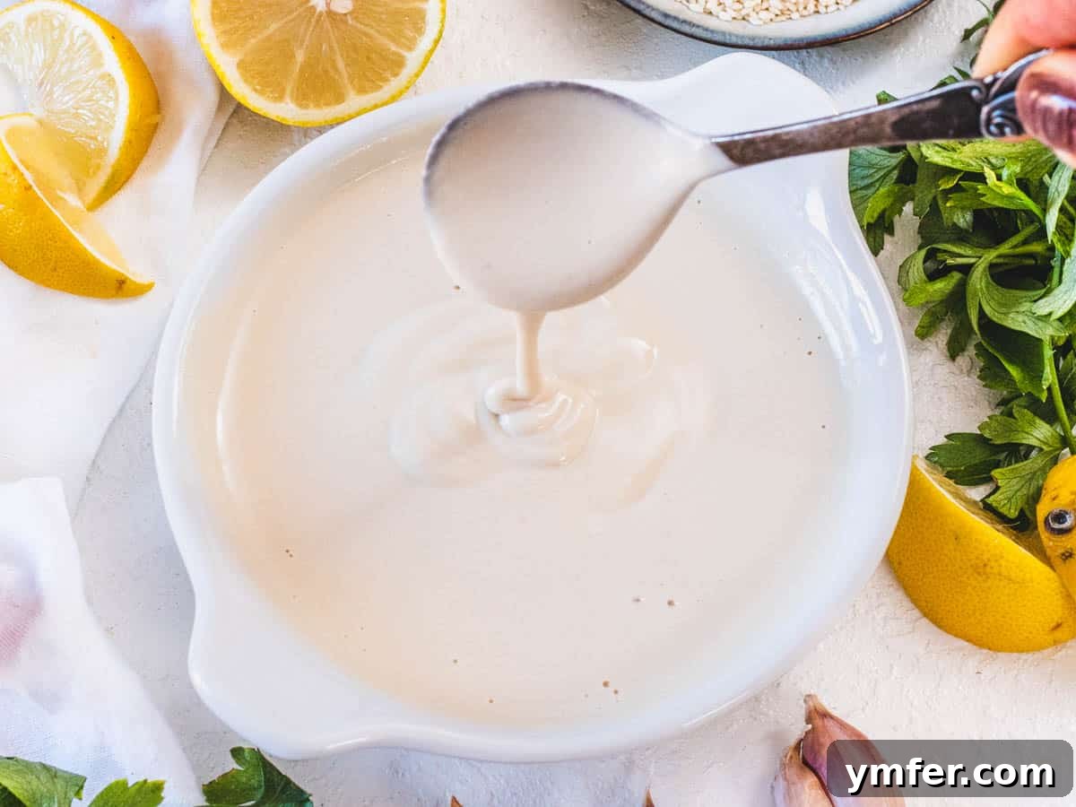 Piyaz Zesty Turkish White Bean Salad 5 Creamy homemade tahini sauce with lemon, water, salt, and garlic, in a glass bowl with a spoon