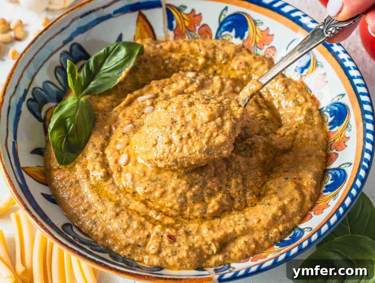 Sicilian Red Pesto 13 red tomato pesto in a blue bowl with a silver spoon