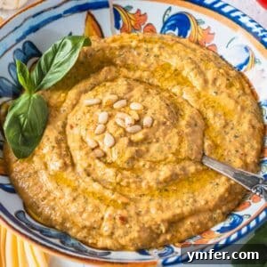 red pesto in a blue bowl with a silver spoon