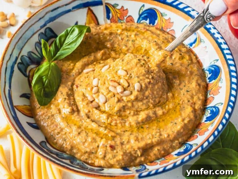 red tomato pesto with pine nuts and hand holding a spoon