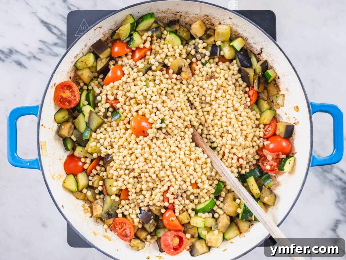 Sardinia's Toasted Pearl Pasta 11 Fregola pasta being added to the sautéed vegetables in a skillet, ready for toasting with a wooden spoon.