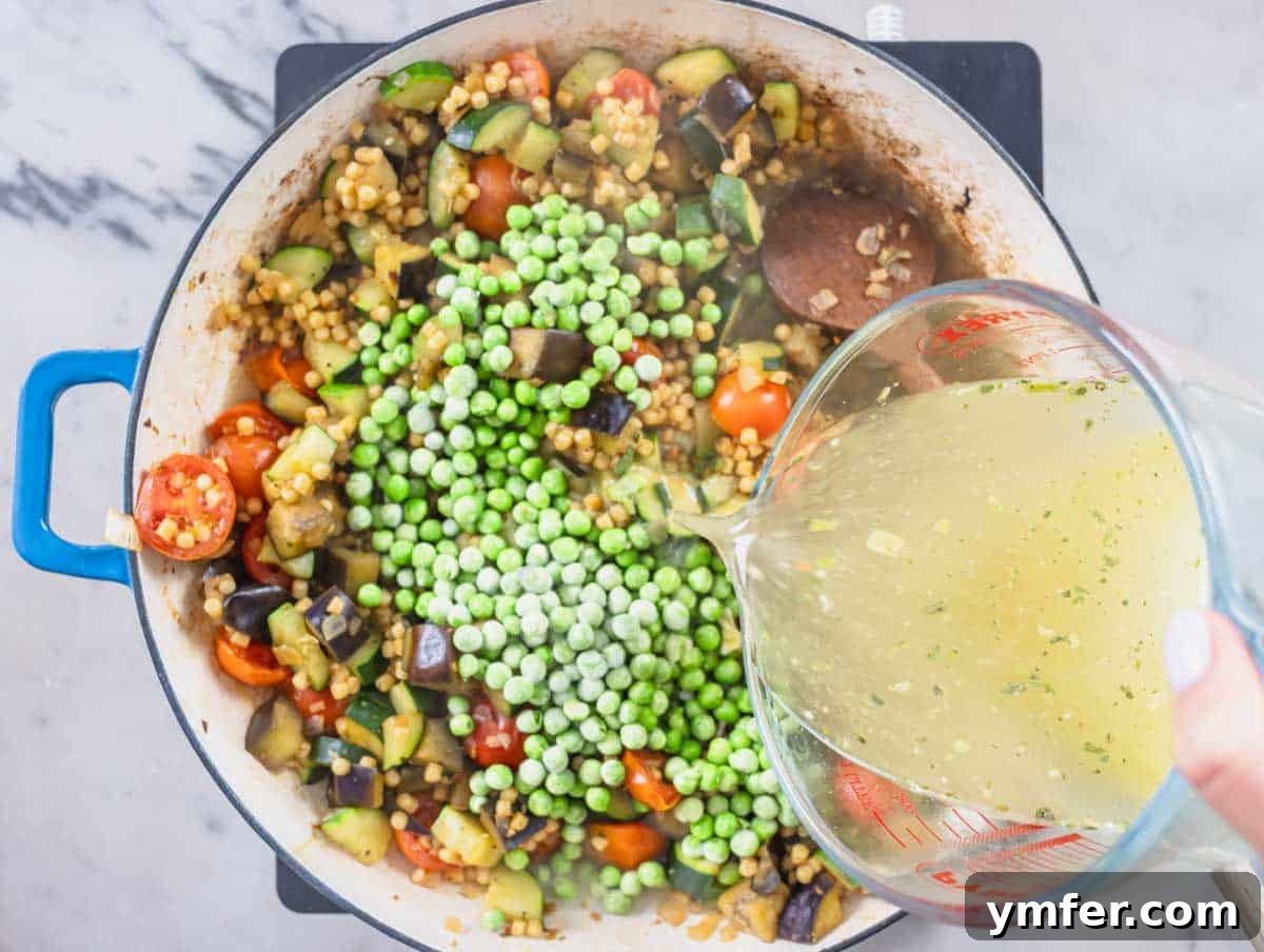 Sardinia's Toasted Pearl Pasta 12 Frozen peas and vegetable broth being added to the skillet with fregola and vegetables, ready to simmer.