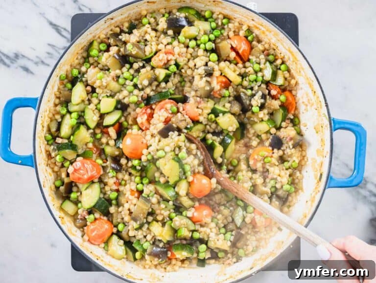 Sardinia's Toasted Pearl Pasta 21 hand cooking vegetables and fregula in a skillet, showing the simmering process.