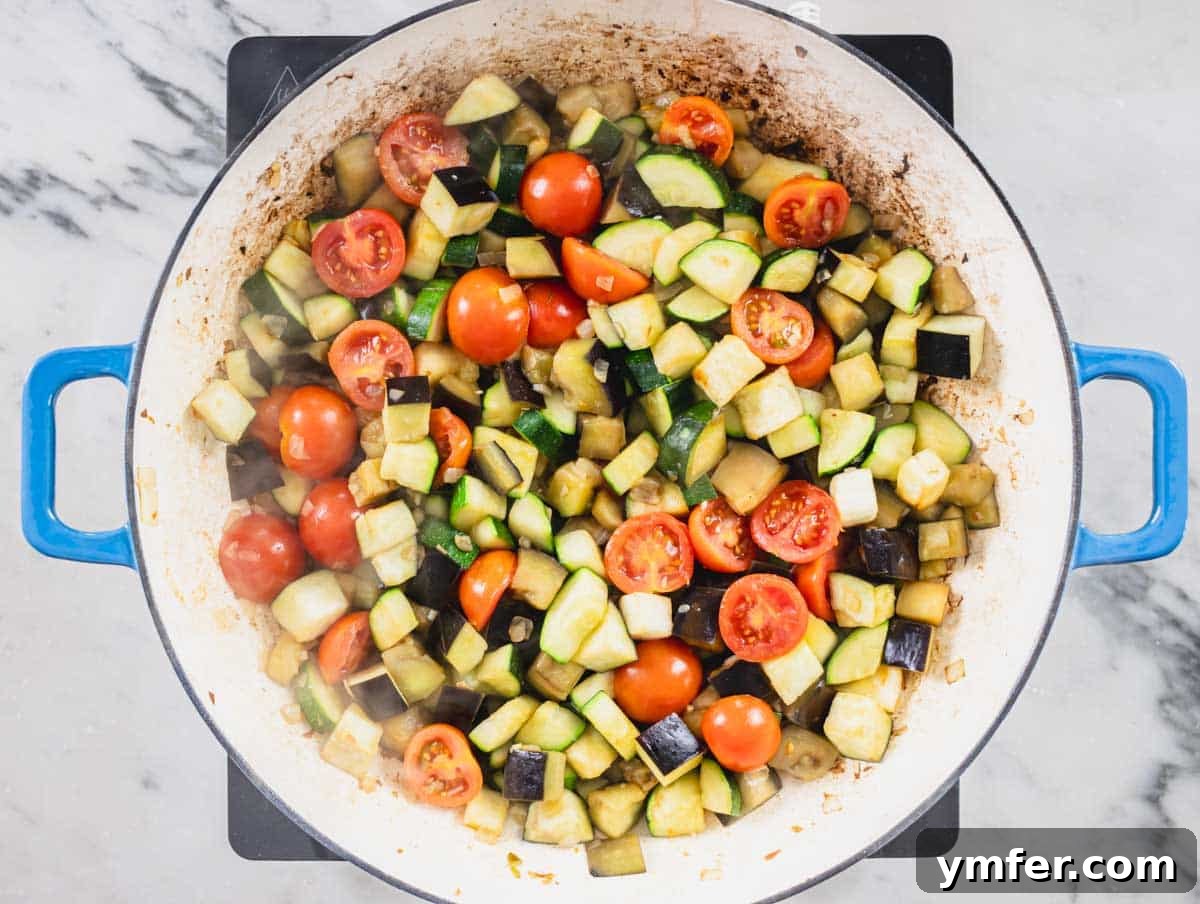 Sardinia's Toasted Pearl Pasta 10 Chopped vegetables and seasonings added to a blue skillet, cooking together.